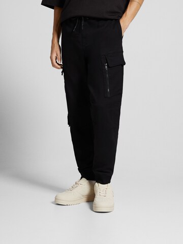 Bershka Tapered Cargo Pants in Black: front